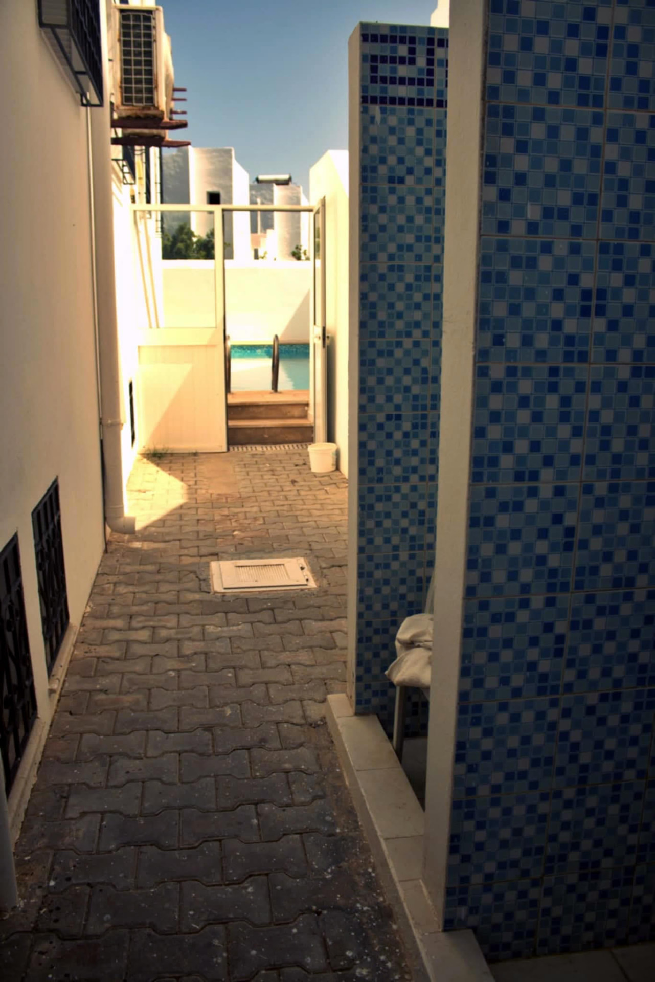 Passage menant à la piscine, murs blancs et mosaïque bleue